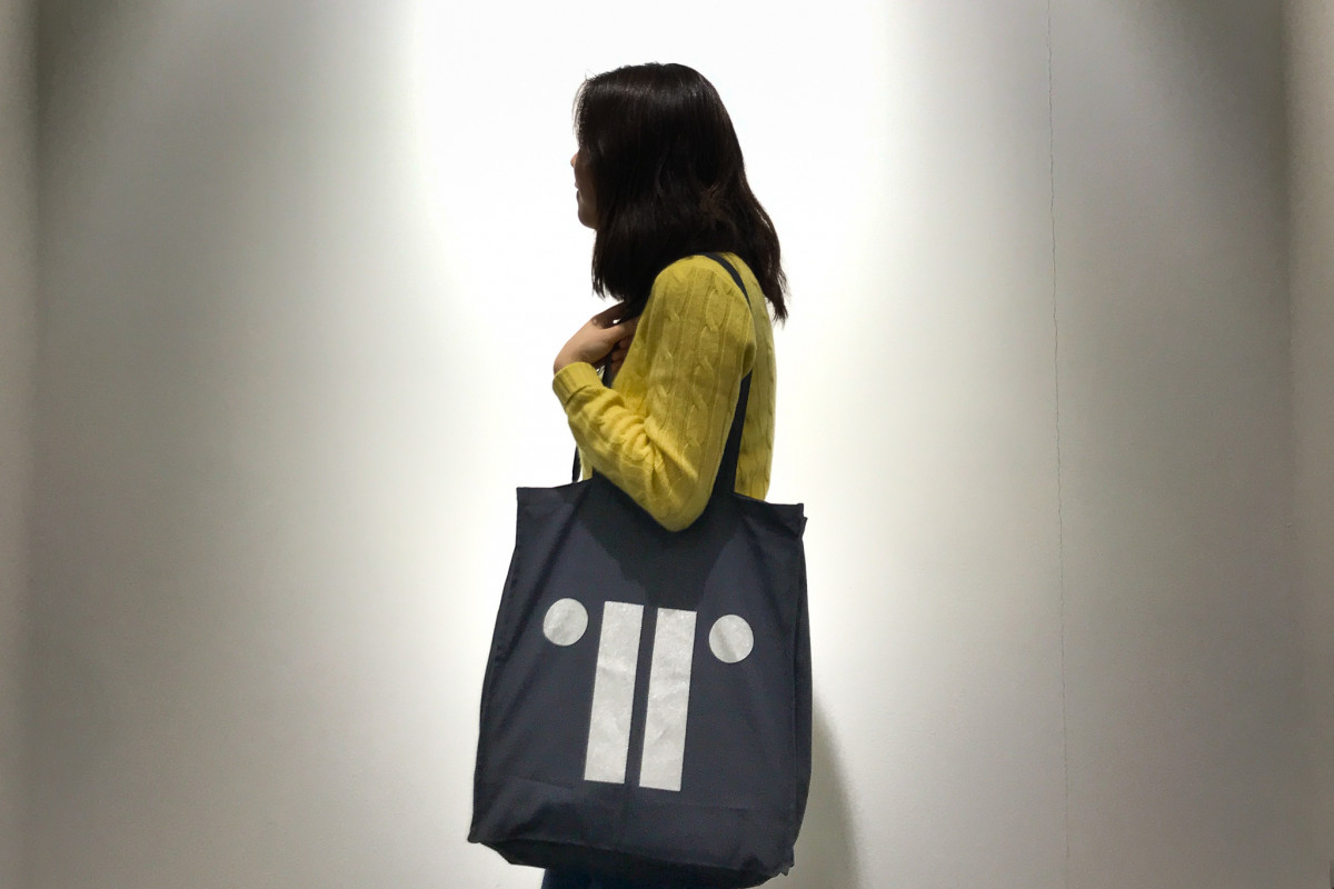 Person wearing bag against white wall