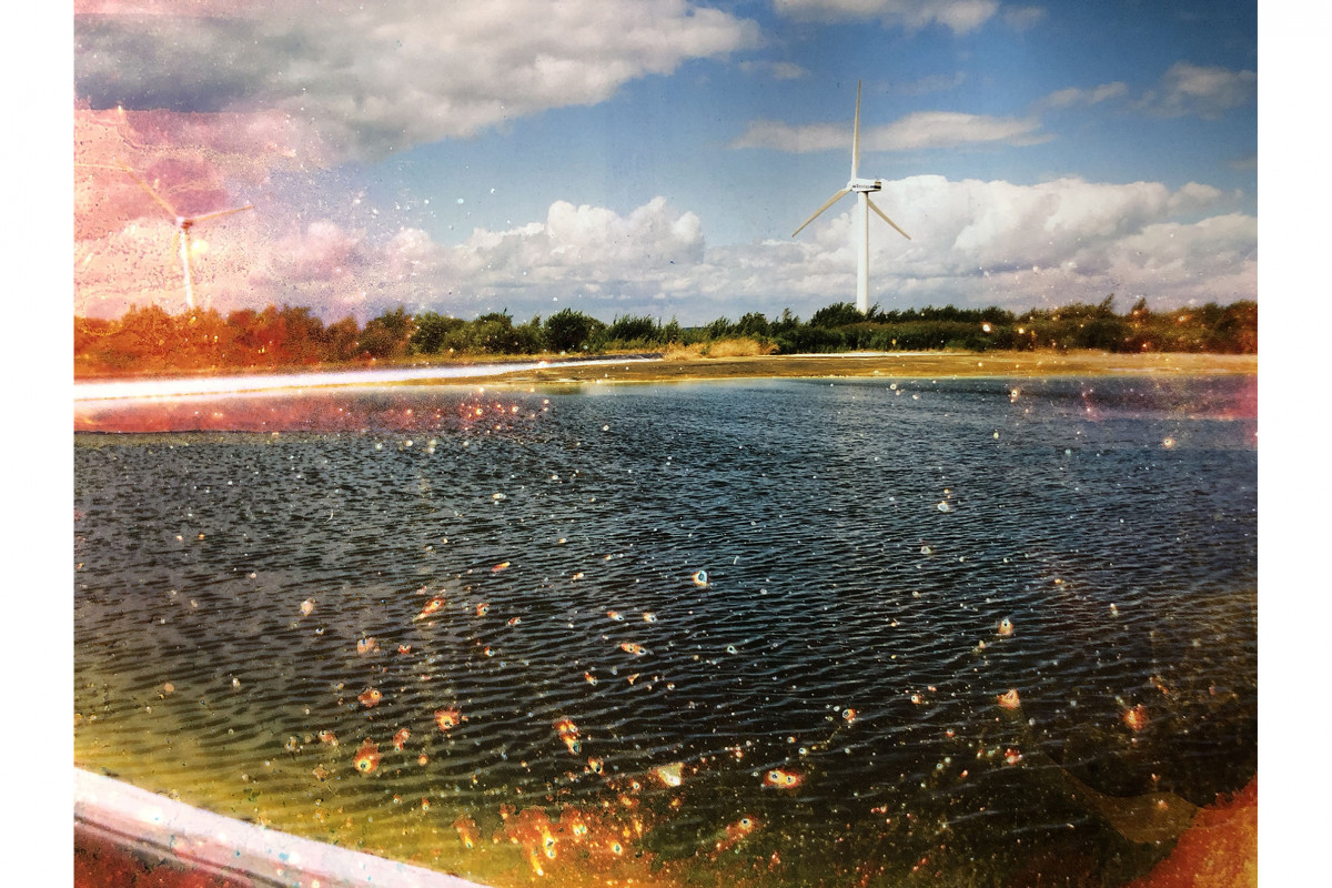 Image of lake with wind turbine in distance