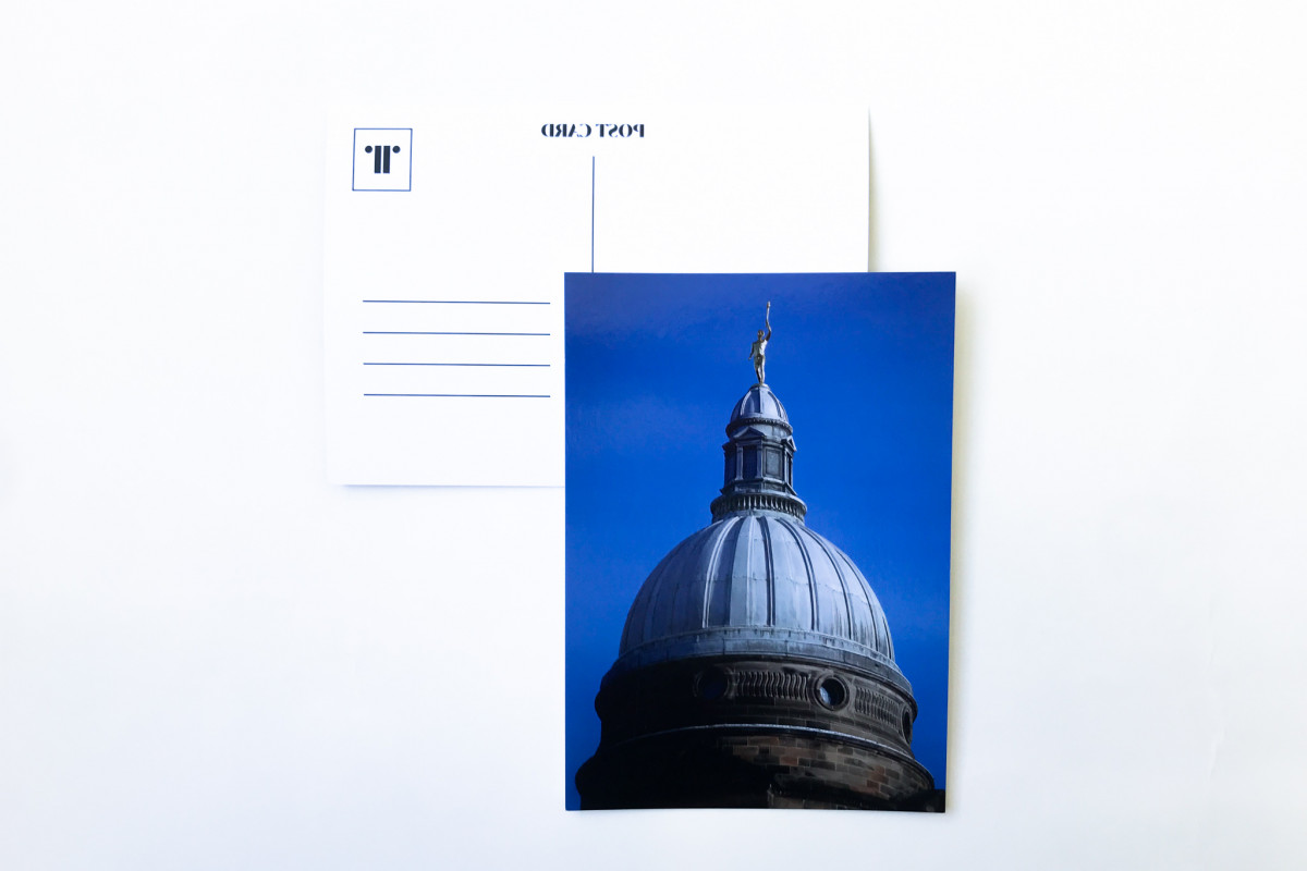 Image of 'Golden Boy' statue on postcard against white background