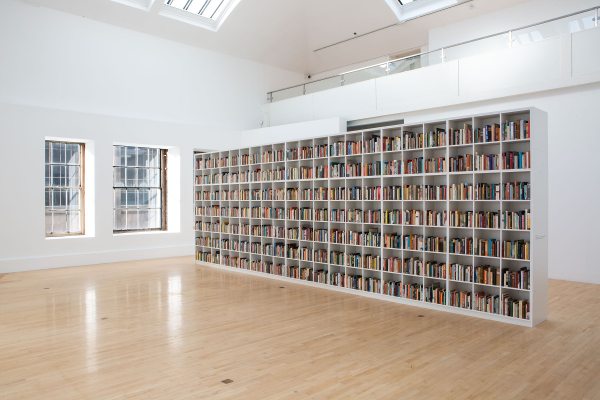 Large white bookshelf in an empty gallery space.