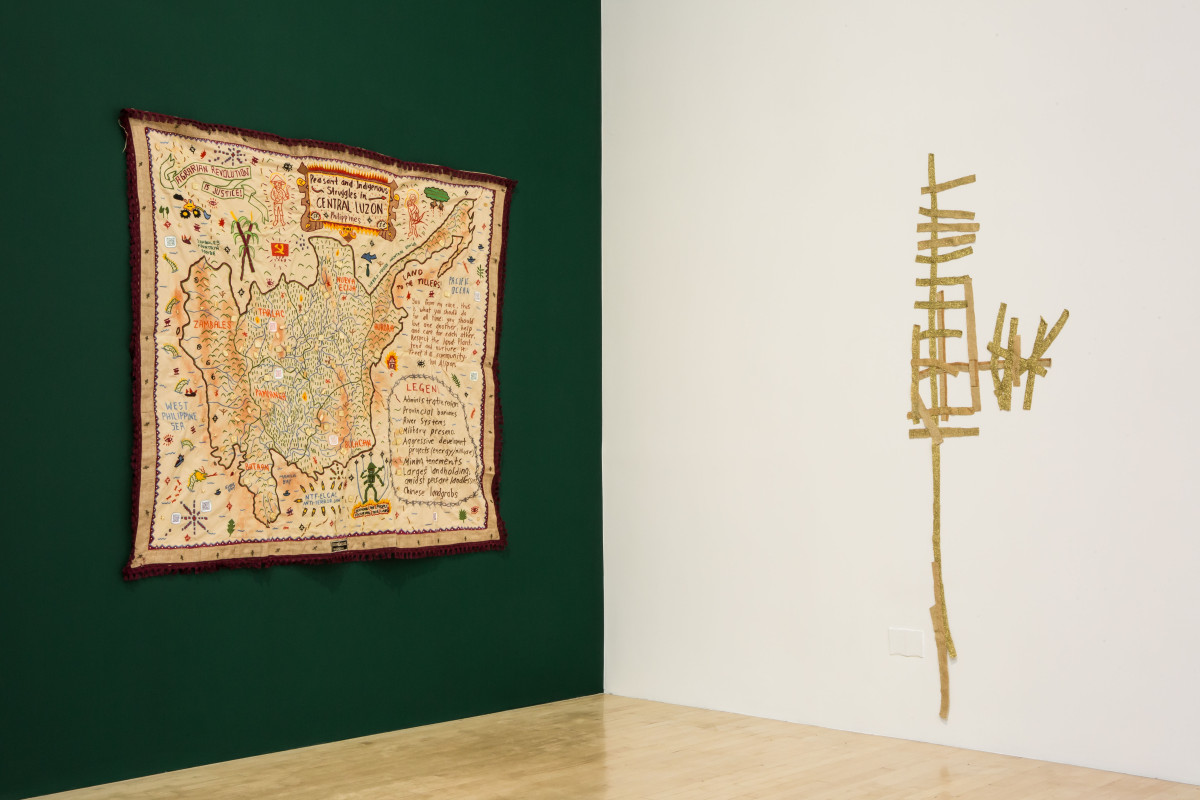 Tapestry on left green wall and arrangement of woven textile on right white wall
