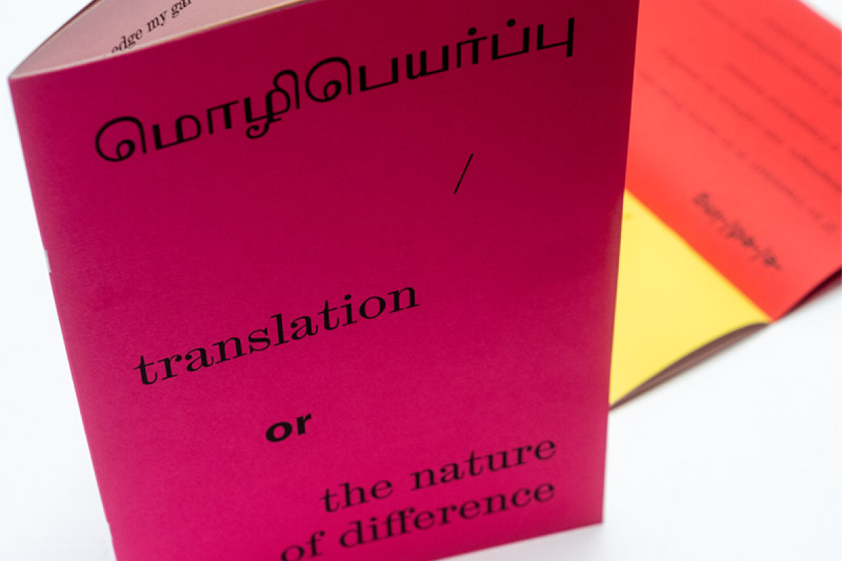 Book standing upright with magenta cover and open page spread behind