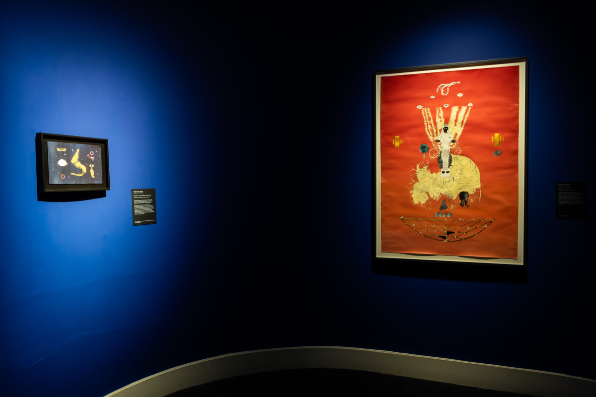 A small dark blue painting and a large orange painting suspended in the gallery's Haunted Room