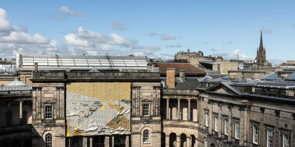 A large scale sculpture hangs from the facade of the University of Edinburgh.